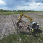 image of an excavator pushing in fence posts