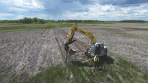 image of an excavator pushing in fence posts