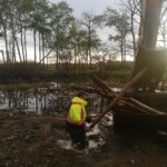 man in a mud pit making a fence