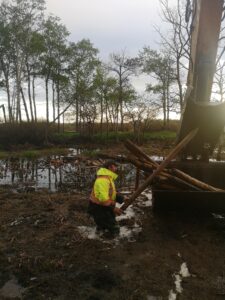 man in a mud pit making a fence