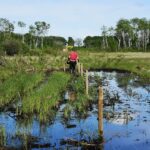 man in mud making fence