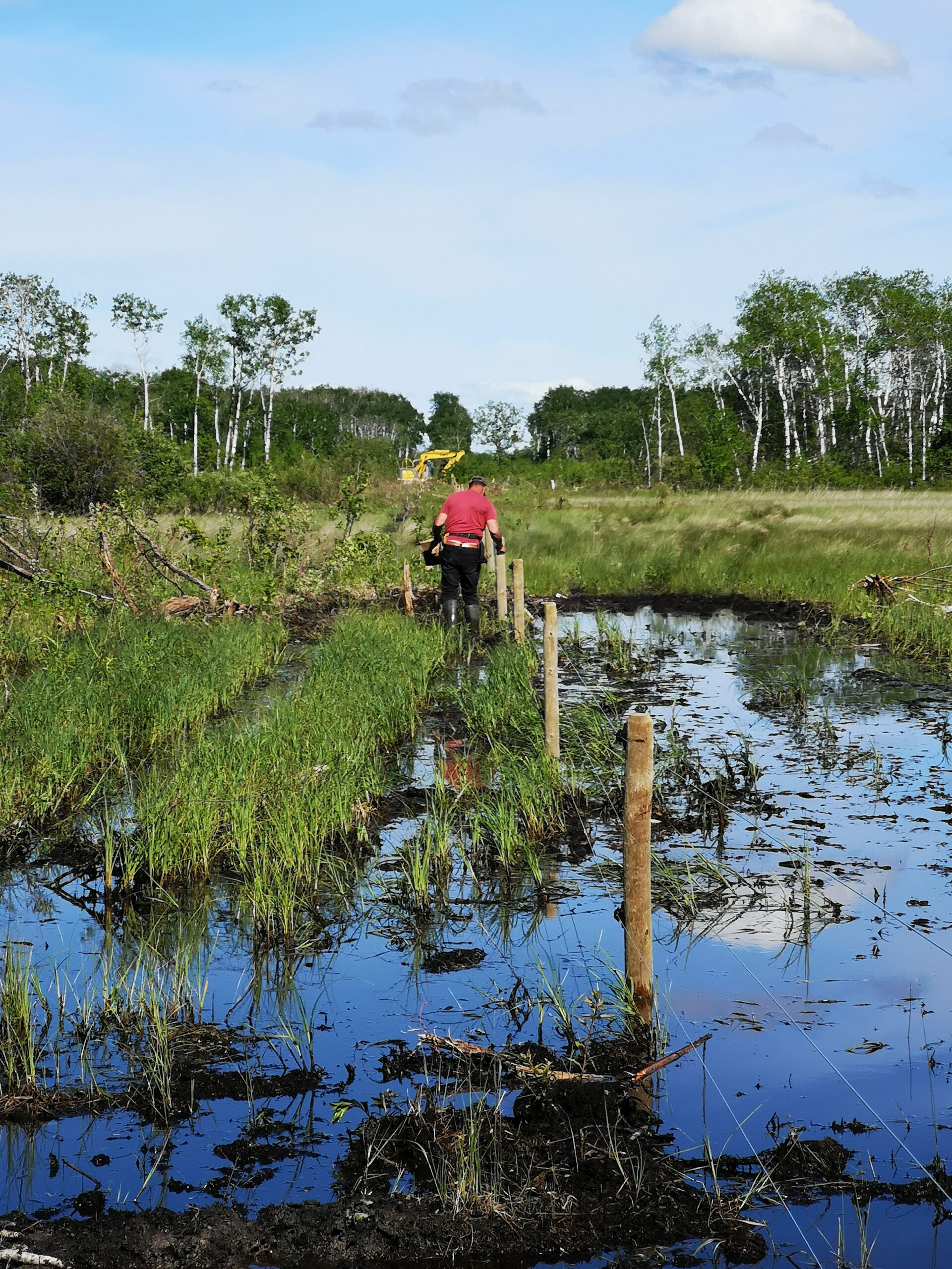 man in mud making fence