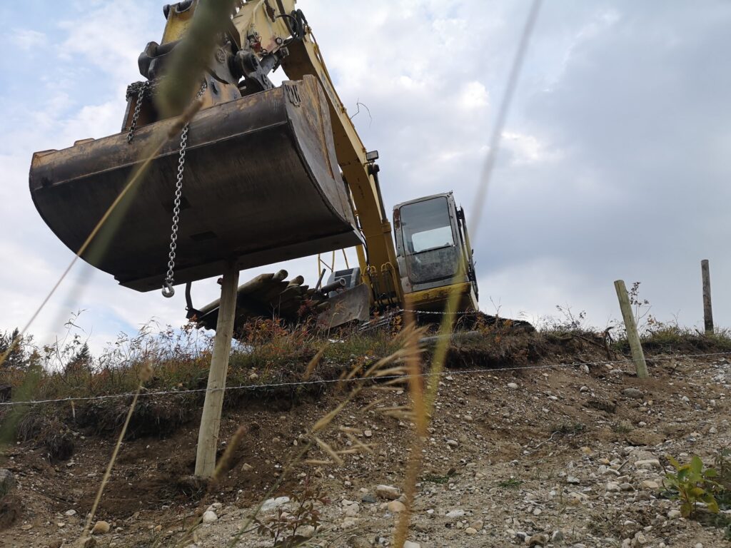 excavator on a hill making a fence