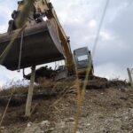 excavator on a hill making a fence